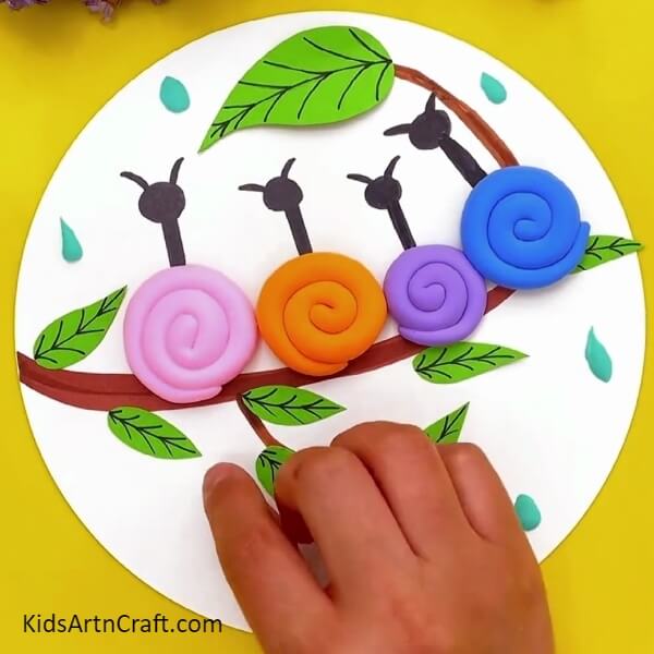 Adding Raindrops- Children's craft project of snails on a tree branch, made of clay-paper. 