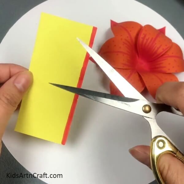 Cutting Strips Of The Yellow Paper- Kids can make a 3D Lily Paper Flower by following this tutorial