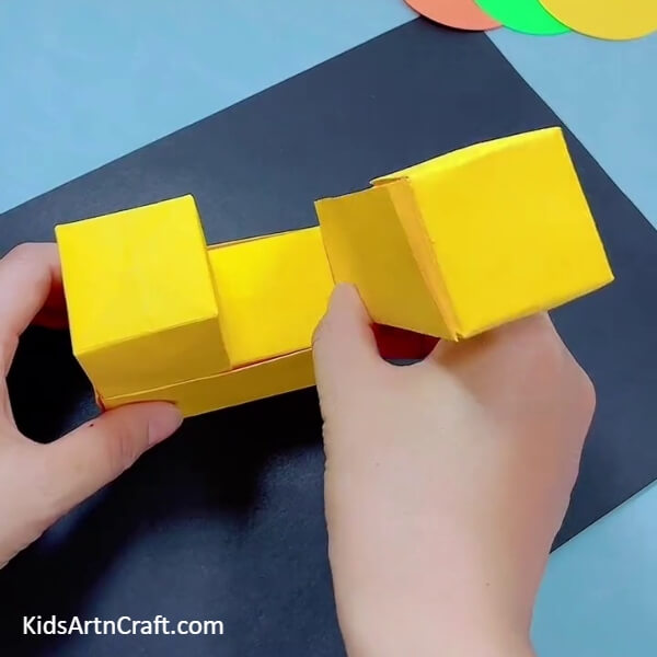 Placing The Strip Inside The Enclosed Box- Learn how to create a Bulldozer using Origami Paper with this tutorial designed for kids