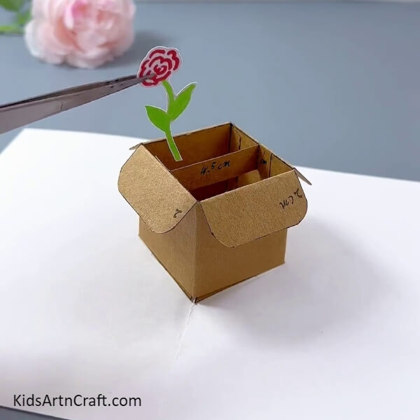 Pasting A Flower Cut Out- Follow along with this tutorial to create a flower pot with a cardboard box for the little ones.