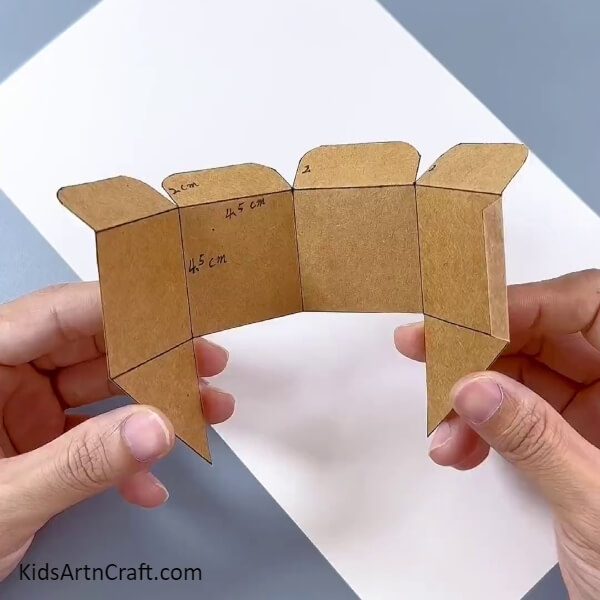 Bending The Carboard Parts Along Pen Outline- A step-by-step guide to crafting a cardboard box flower pot for kids