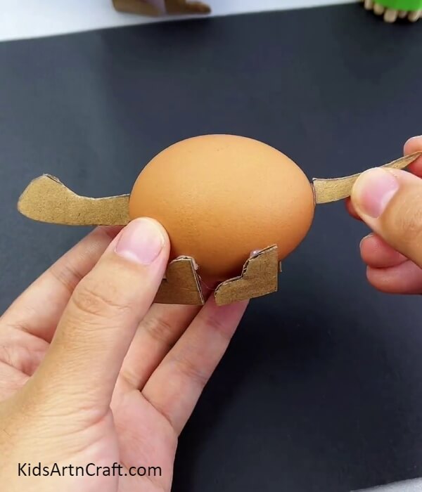 Pasting The Tail Of The Dinosaur- Guide to Constructing a Dinosaur Model with Egg Shells and Cardboard