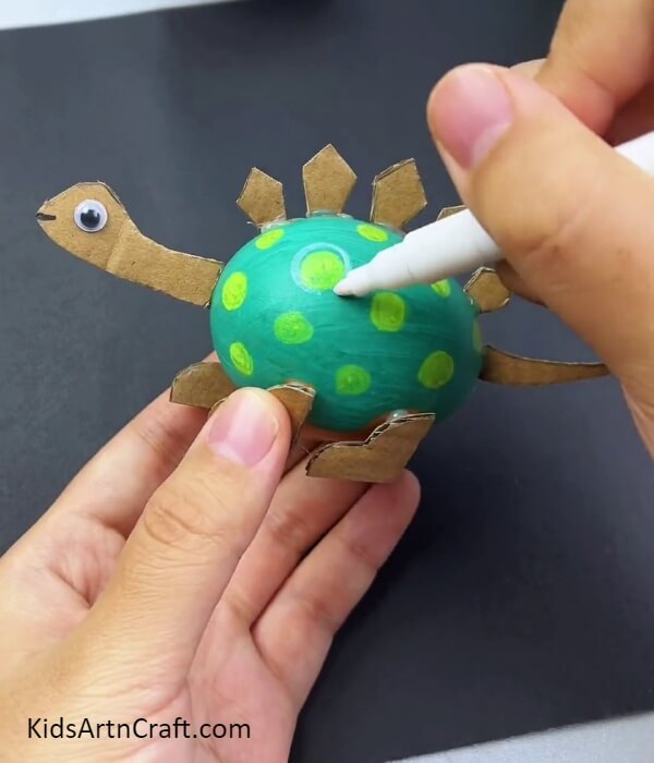 Coloring The Dinosaur Body And Pasting A Googly Eye- Tutorial on Crafting a Dinosaur Model with Egg Shells and Cardboard