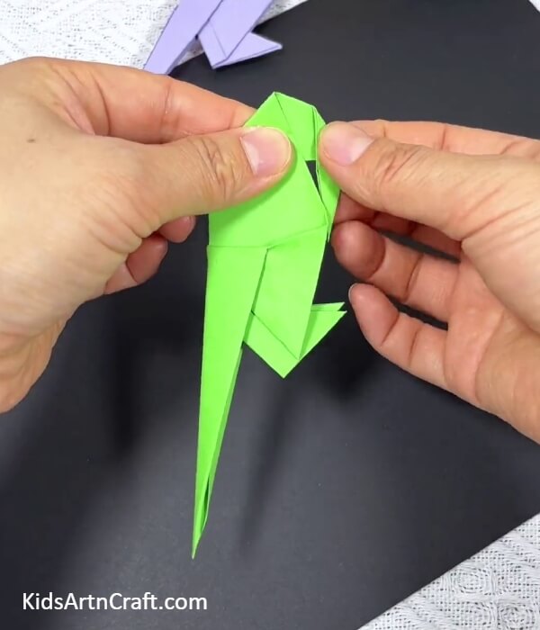 forming The Beak Of The Parrot-Demonstrating origami parrot creations to children