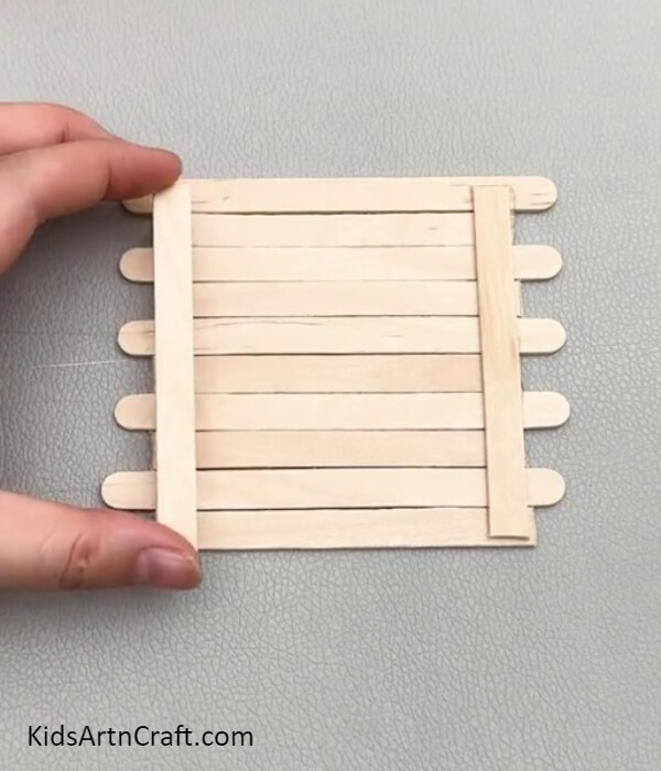 Sticking 2 Popsicle Sticks Over Hot Glue- Crafting a Small House with Popsicle Sticks: A Tutorial for Kids