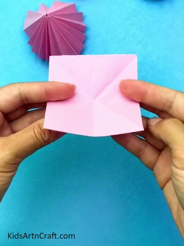 Making Creases On Another Pink Paper- Step-by-step guide for making an origami dress with children