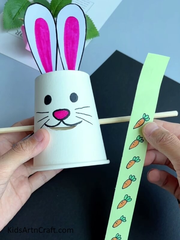 Making Carrots On A Paper Strip- Paper cup bunny eating carrot - a great craft idea for children.