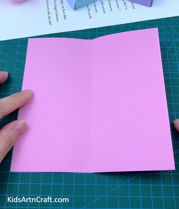 Folding A Pink Paper To Middle Crease-Making a Bed and Cushion Out of Paper for Children
