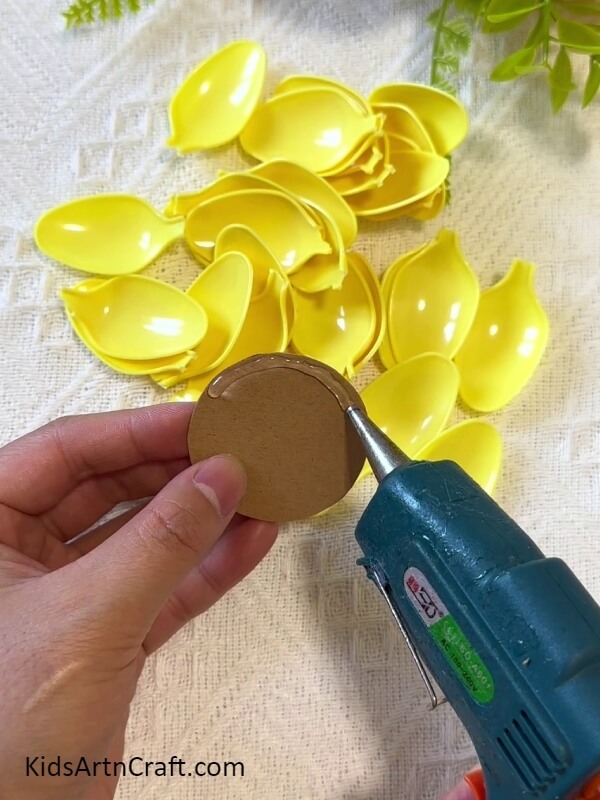 Applying Hot Glue On A Cardboard Circle-How to Assemble a Sunflower out of Plastic Spoons with Kids 