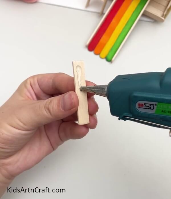 Applying Hot Glue Over A Popsicle Stick Piece- Directions to Assemble a Slider Model Out of Popsicle Sticks for Children