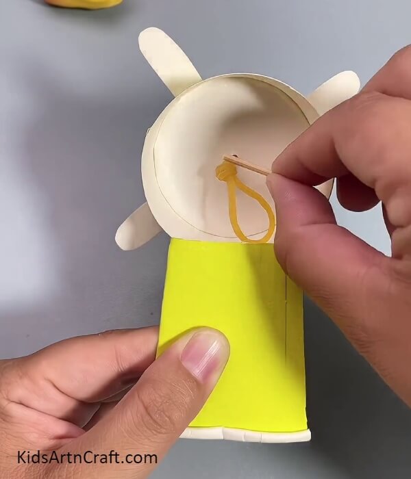 Inserting A Stick In The Rubber Band- Crafting Guide For Making A Fan Using Reused Paper Cups For Little Ones