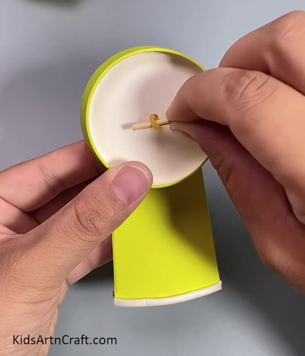 Securing The Band With Stick- A tutorial showing kids how to make a fan from used paper cups