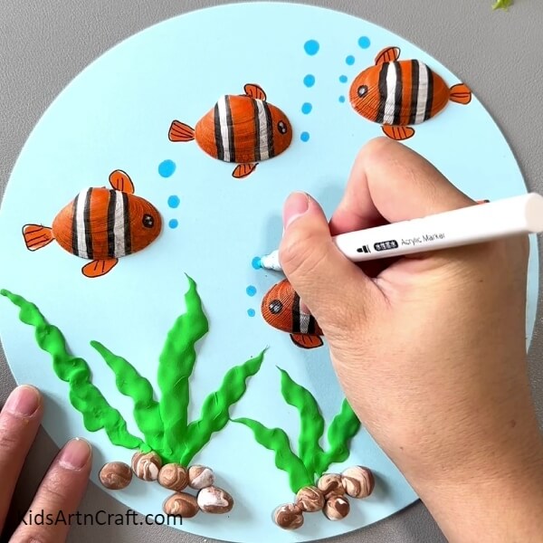Detailing The Fins And Tails And Making Bubbles- Step-by-step instructions for constructing art pieces with shells, goldfish, paper and clay. 